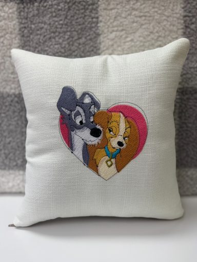 A decorative cushion featuring a cartoon dog couple inside a heart.