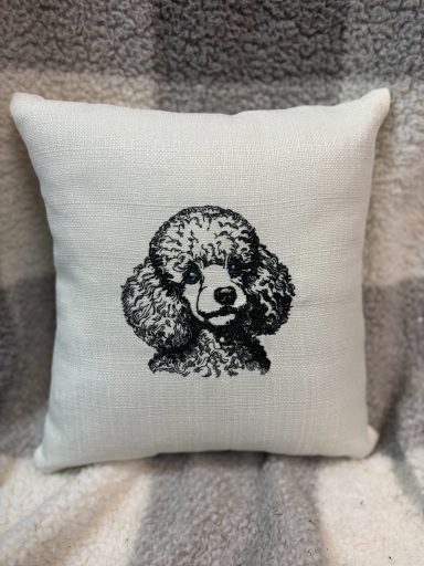 A decorative cushion featuring an embroidered poodle design.
