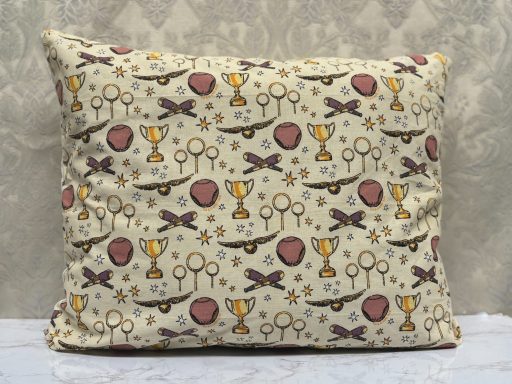 Cushion with a decorative pattern of trophies, ribbons, and shields in muted colours.