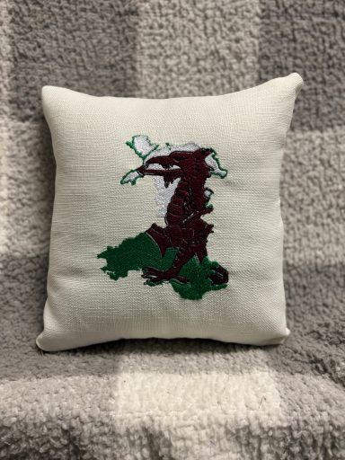 Cushion featuring a maroon dragon design on a green background.