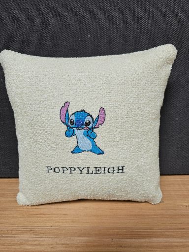 A soft cushion featuring an embroidered blue cartoon character with large ears and the name can be changed to what ever is required