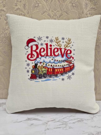 Decorative cushion featuring the word "Believe" and a festive train design.