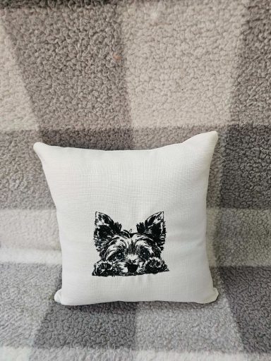 A white cushion featuring a black and white dog illustration.