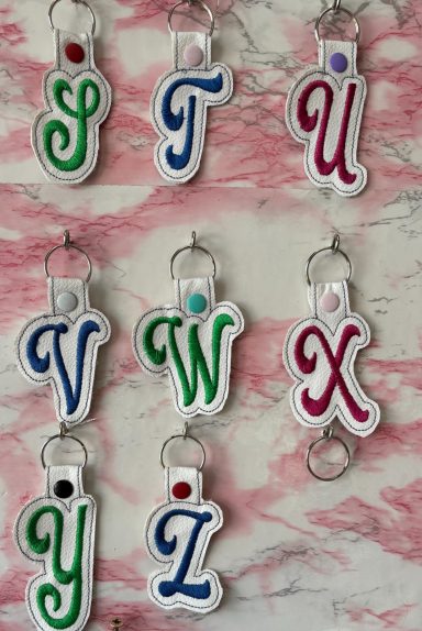 Keychains displaying the letters S, T, U, V, W, X, Y, and Z in colourful designs.