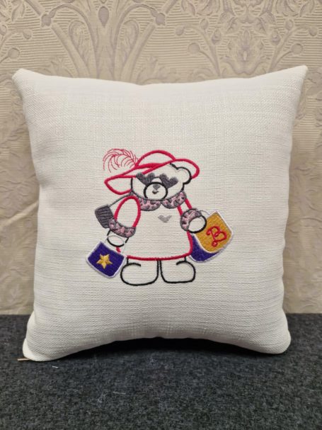 A fluffy cushion featuring a cartoon bear in a chef's outfit, holding cooking tools.