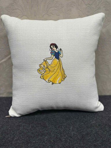 White cushion featuring an embroidered image of Snow White in her iconic dress.