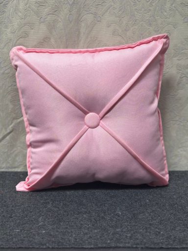 Square pink cushion with decorative stitching and a central button.