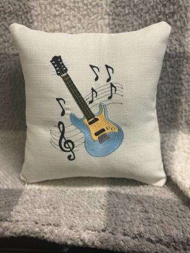 A decorative pillow featuring a blue guitar and musical notes.