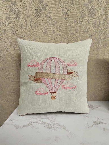 Cream cushion featuring a pink hot air balloon and decorative clouds.