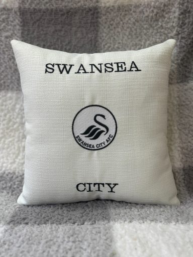 White cushion with "Swansea City" text and a swan logo.