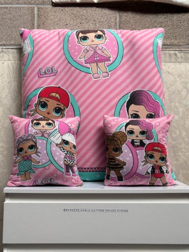 A set of plush cushions featuring various cartoon characters on a pink striped background.