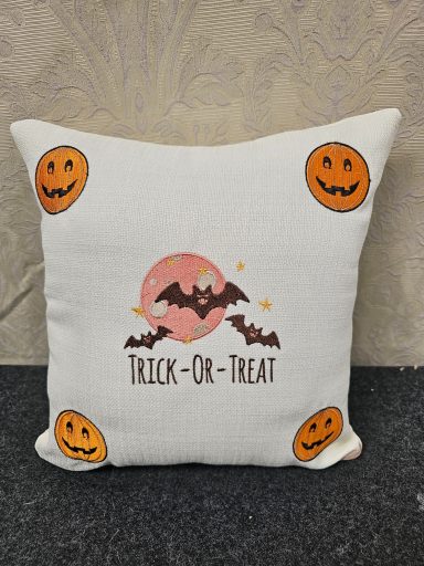 White cushion featuring "Trick-Or-Treat" text, bats, and orange pumpkin designs.