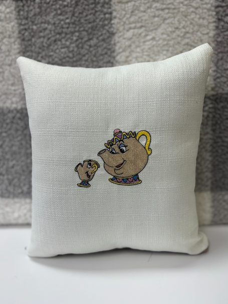 Embroidered cushion featuring a teapot and teacup design on a white background.