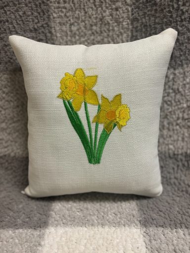 White cushion featuring a yellow daffodil design on the front.