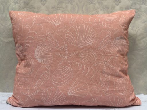 Pink cushion with a subtle shell pattern on a textured background.