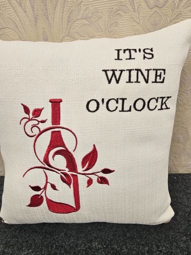 Cushion with text "It's wine o'clock" and a decorative wine bottle and vine design.