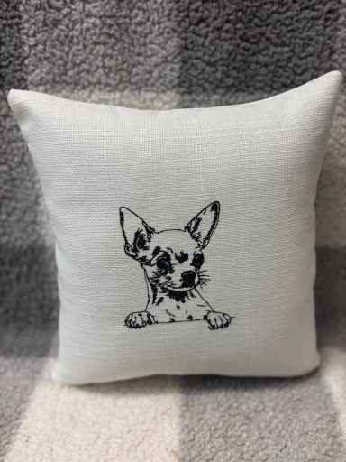 White cushion featuring a black line drawing of a Chihuahua.