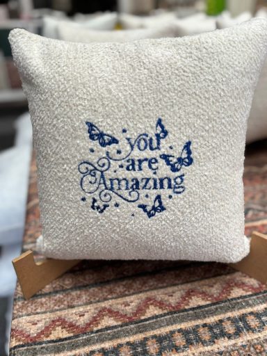 Decorative cushion with the text "You Are Amazing" and butterfly designs.