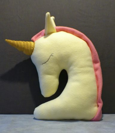 Soft, plush unicorn head with a golden horn and pink mane, tilted to one side.