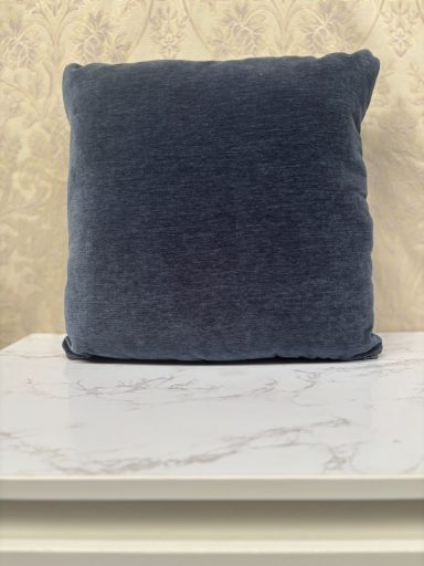 Square blue cushion on a marble surface against a light textured background.