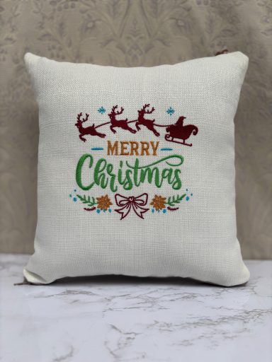 Pillow featuring "Merry Christmas" with reindeer and festive decorations.