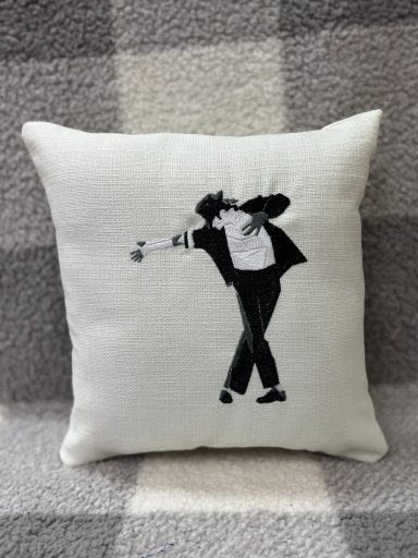 Black silhouette of a dancer in a tuxedo on a light cushion.