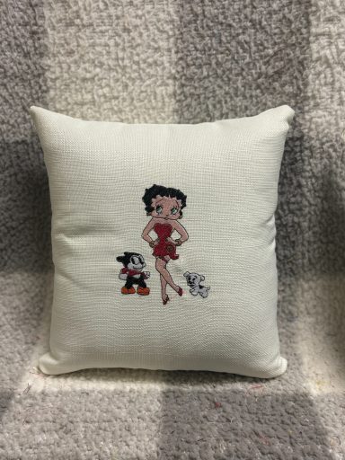 A decorative pillow featuring Betty Boop and a small cartoon character.
