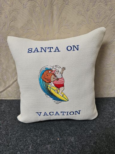 A decorative cushion featuring Santa surfing with the text "Santa on Vacation."