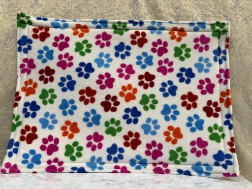 Pattern of colourful paw prints on a white background.