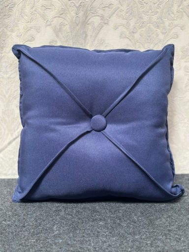 Navy blue cushion with a button in the centre and stitched corner detailing.