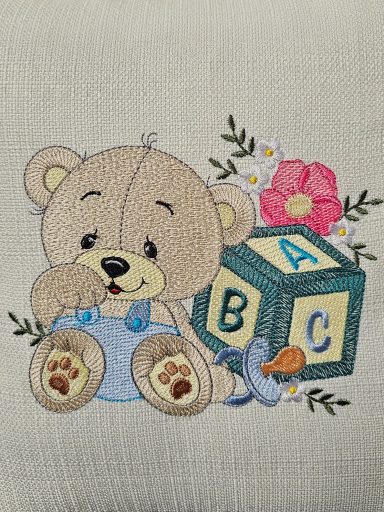 Cartoon teddy bear in overalls with blocks, a pacifier, and flowers.