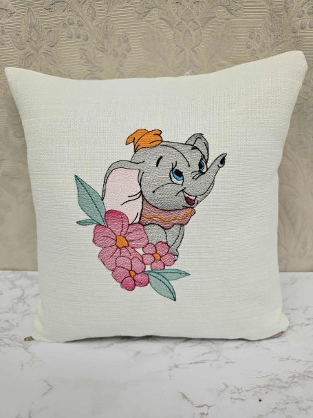 A decorative cushion featuring a cartoon elephant with flowers.