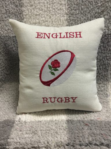 Decorative cushion with "English Rugby" text and a rose emblem.