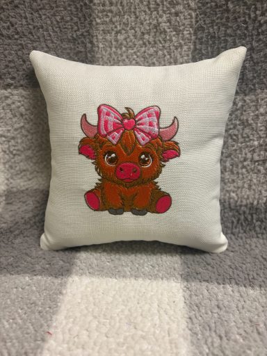 Cute plush cushion featuring a cartoon cow with a pink bow.