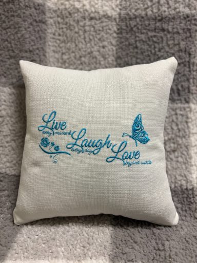 Square cushion with "Live Laugh Love" in blue text and a butterfly design.