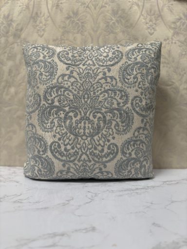 Square cushion with a blue and cream damask pattern on a textured background.