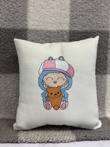 Cute cushion featuring a character in a blue outfit holding a brown teddy bear.