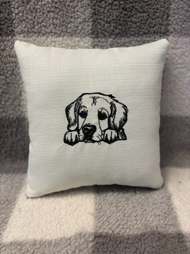 White cushion with a black illustration of a dog’s head resting on its paws.