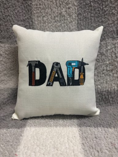 A decorative cushion featuring the word "DAD" in a colourful, stylised font.