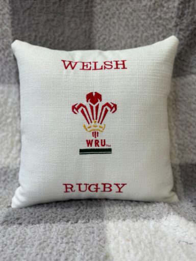 White cushion with red Welsh Rugby emblem and text "WELSH RUGBY" and "WRU".