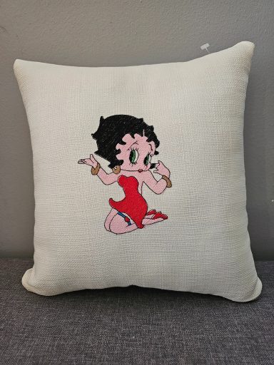 A decorative cushion featuring a cartoon character in a red dress.