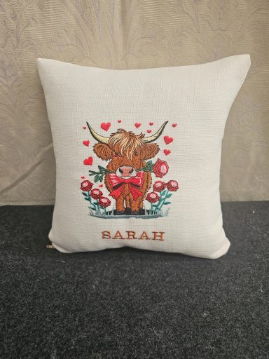 Cushion with a cartoonish cow, hearts, and floral accents, featuring the name "Sarah."