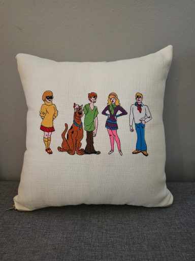 Four characters from a cartoon with a dog, standing in a row on a cushion.
