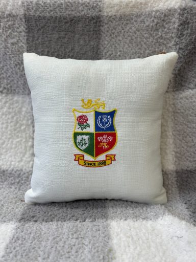 Cushion featuring a colourful coat of arms on a white background.
