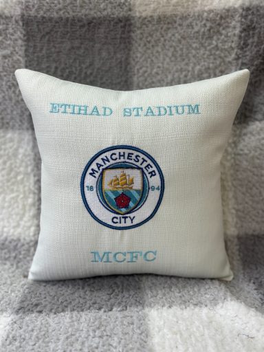 White cushion featuring the Manchester City FC logo and "Etihad Stadium" text.