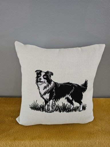 Cushion featuring a black and white illustration of a dog in a grassy setting.
