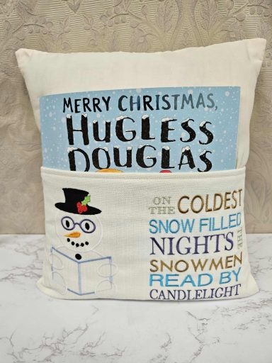 Cushion featuring a festive theme with "Merry Christmas, Hugless Douglas" and snowman designs.