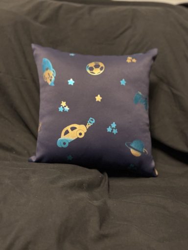 Navy cushion featuring whimsical space-themed illustrations, including planets and a spaceship.