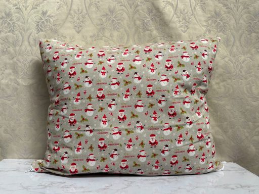 Decorative cushion covered in a festive Santa and Christmas pattern.