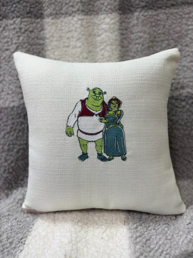 Green ogre and princess character embroidered on a decorative cushion.